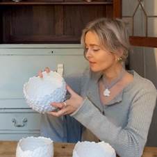 A person holding a white bowl  Description automatically generated