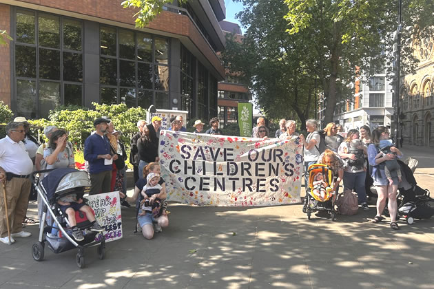 Protestors hold up a banner outside Perceval House 