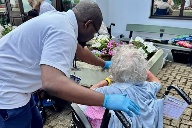 A member of staff assists a patient with her gardening 